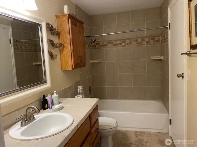 This is the upstairs bathroom with it's tile counters, flooring and bathtub surround.