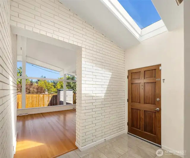 The stylish foyer is flooded with natural light from the vaulted skylight and showcases the beautiful brick detail featured throughout the home.