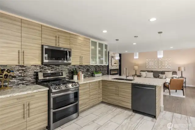 Lovely kitchen upgrades include stylish countertop and backsplash, modern cabinetry and tile flooring