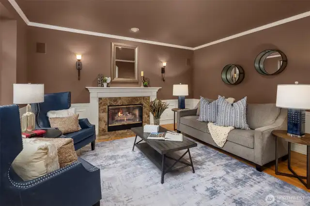 To the left, the formal living room features a gas fireplace and wainscoting and crown molding.  Hardwood floors all throughout the home.