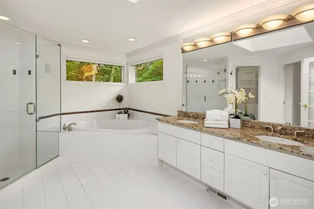 Frameless shower, soaking tub and double sink vanity.  From the mirror you can see the fully built-out walk-in closet, as well as the door to the WC.