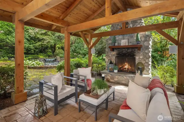 Outdoor gazebo, with exposed beams, tile floors, river rock wood burning fireplace.  Gazebo features plenty of space for seating - watching a football game in the rain with a roaring fire has never been so fun!  Note the majestic fountain just across the way.  Utter privacy throughout the entire yard.