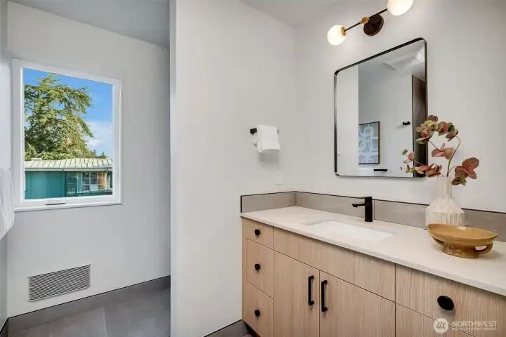 The light wood with contrasting fixtures and large-format ceramic tile floors in the top floor primary bathroom.