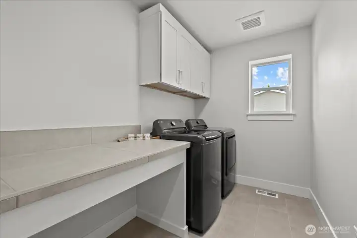 Upstairs laundry room with counterspace and storage.