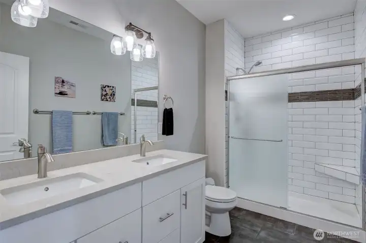 Stylish primary bathroom includes quartz double vanity and custom walk-in shower.