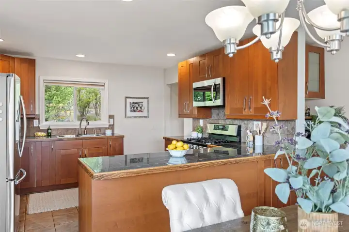 Chefs kitchen with an abundance of cabinets, granite counters under-cabinet lighting, tiled flooring and a tiled backsplash.