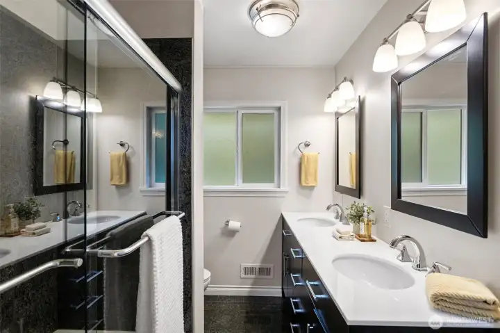 Full bathroom on main level features a double quartz vanity, granite bath surround, glass shower doors and stainless hardware.