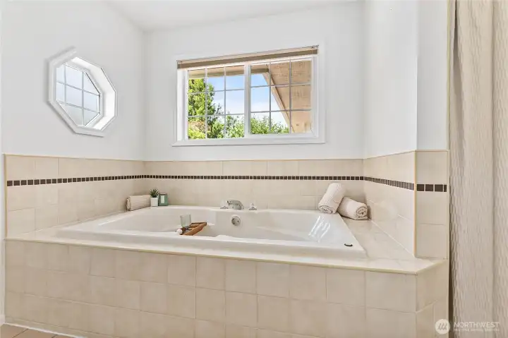 Equipped with a jetted tub, double sink vanity, and a separate shower.