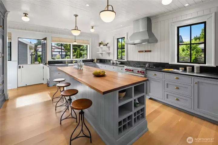 The stunning chef’s kitchen features an expansive walnut island, Wolf appliances, Sub-Zero refrigerator, soapstone counters, and a beautiful Shaw’s farmhouse sink, anchoring the home and flowing seamlessly into the dining room.