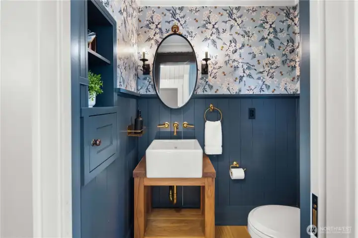 The sophisticated main floor offers elegant yet comfortable living spaces, including a beautifully appointed living room and stylish powder room accented with designer wallpaper, oak hardwoods, and another Shaw’s sink.