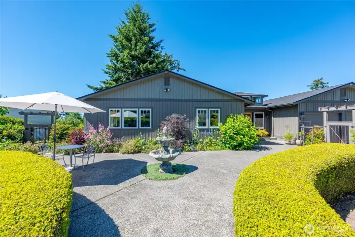 Expansive fenced in front patio with exposed aggregate and water feature.