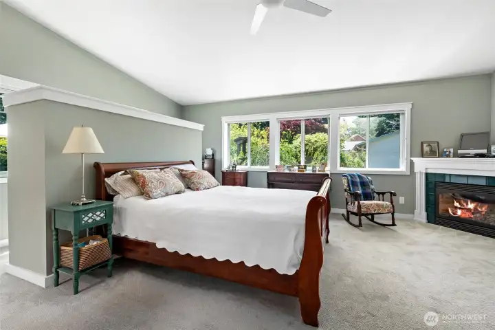 Primary bedroom on main level with vaulted ceiling, and propane fireplace. The half wall partition creates a private home office alcove