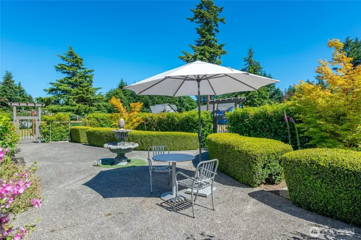 Expansive exposed aggregate front patio with water feature and beautiful landscaping.