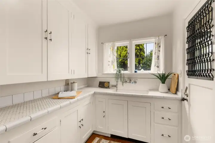 The kitchen is bright with original countertops, good cabinet space, lead trimmed windows, high ceilings, and a back door.