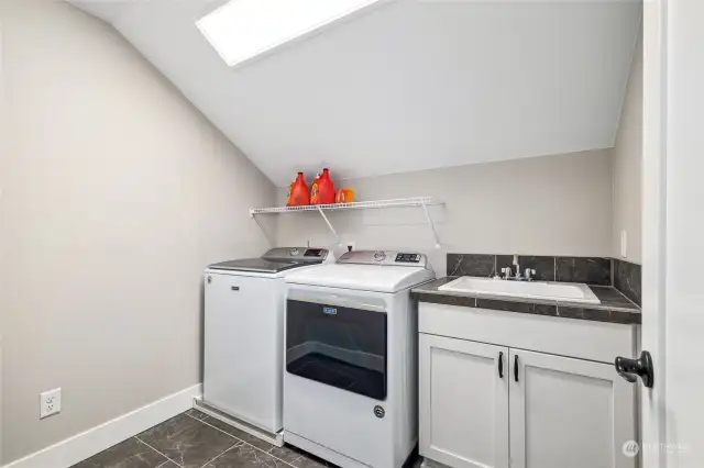 The luminous and chic laundry room on the upper floor includes a utility sink cabinet.