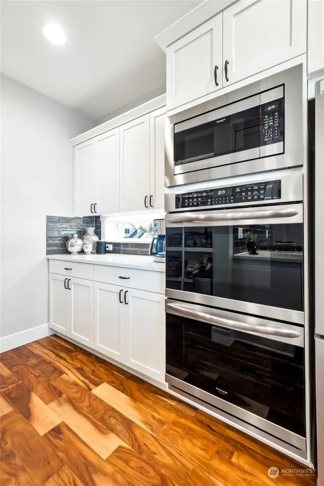 The well-appointed kitchen features sleek stainless steel appliances, including a double oven and gas range, along with a highly functional coffee bar area opposite a meticulously organized walk-in pantry.
