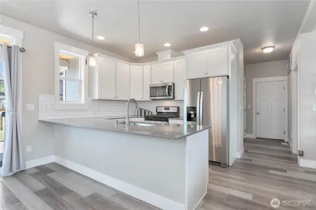 Kitchen with breakfast bar. Entrance to the garage is straight down the hall, with laundry room to the right.