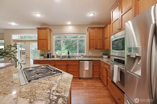 Bright and open kitchen just off the dining room, featuring a large granite center island with gas cooktop, and updated appliances. Significant cabinet space, rich wood cabinetry, and a picture window overlooking the serene backyard complete this perfect gathering space for everyday living or entertaining.