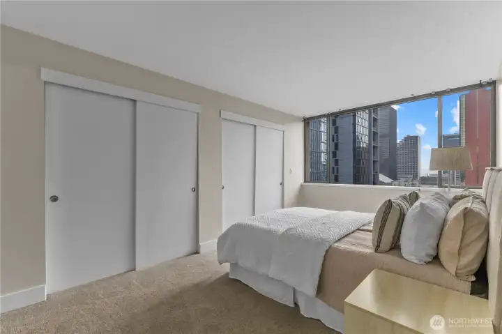 Spacious primary suite with double closets and skyline backdrop.