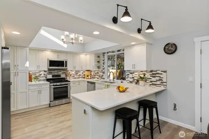 Start your mornings in this light-filled kitchen, featuring a skylight with motorized blinds and a large peninsula that makes the space feel bright, open, and inviting.