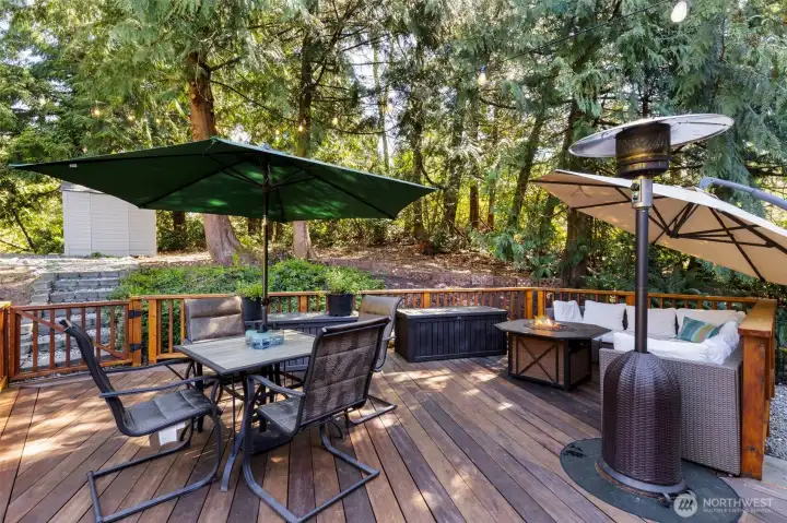 Step out onto the expansive deck, where mature evergreens, multiple seating areas, and soft café lighting create the perfect setting for year-round enjoyment.
