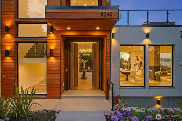 An inviting entry framed in warm wood and glass, opening to artful interiors and a glimpse of Lake Washington beyond.