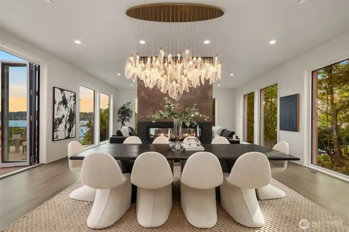 Wall-to-wall windows, operable glass walls, a sculptural chandelier, and a double-sided fireplace set the stage for dining with style and a view.