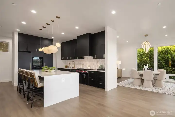 An open-concept kitchen and casual dining area, where bold design meets a backdrop of lush greenery for a fresh, inviting atmosphere