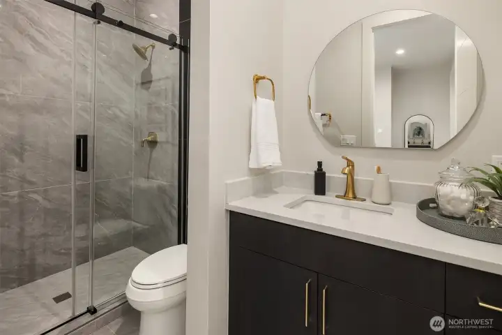 Ensuite bath with sleek stone tile, brushed gold fixtures, and a picture window bringing in natural light
