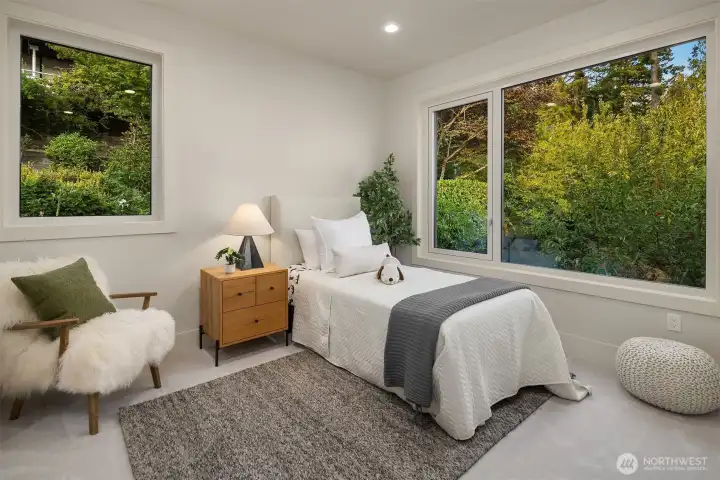 Another of the four upper-level bedrooms, this serene space connects to a Jack-and-Jill bathroom and overlooks lush, private greenery