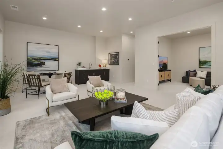 Spacious lower-level rec room with game area, wet bar, and adjacent media room—perfect for entertaining or relaxing at home