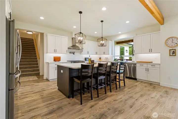 This great kitchen photo really showcases the design aspect the builder had in mind with the pendant chandeliers, custom cabinetry locally made in Ferndale, and the large island to gather around. Stairs ahead leads to the large bonus room that's situated over the garage.