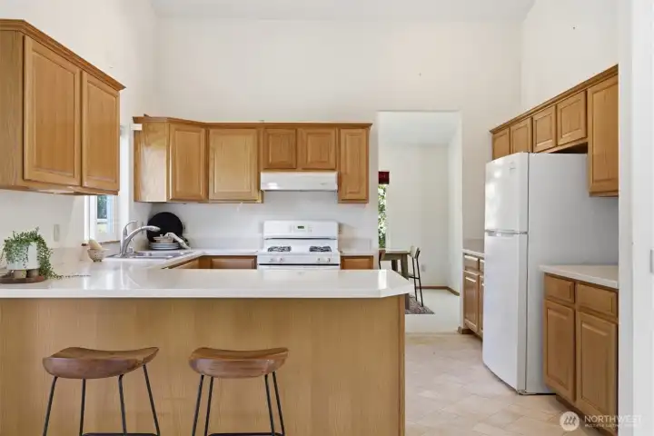 The kitchen has light oak cabinets with white appliances that highlight the countertops.