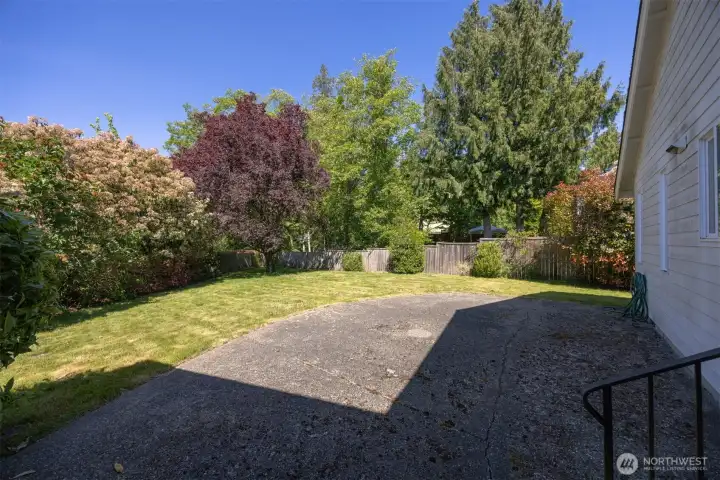 There is a large patio on the north side of the home with a large yard lined with shrubery.