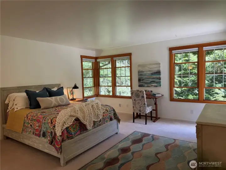 Spacious primary bedroom with lots of natural light coming through multiple windows and a set of French doors that open to the deck. Spacious primary bedroom with lots of natural light coming through multiple windows and a set of French doors that open to the deck.
