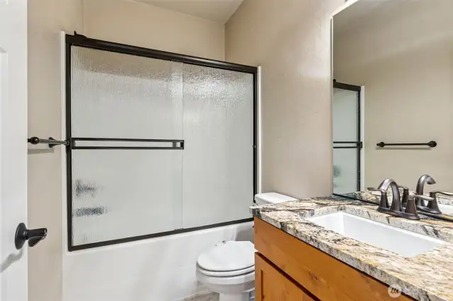 Main full bath has tile floors and granite countertops.