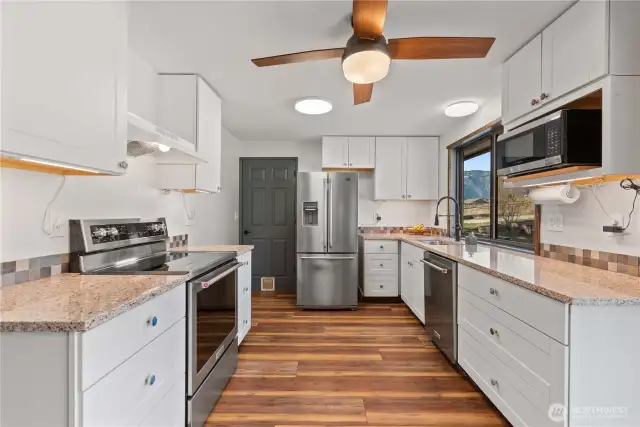 The kitchen features new appliances and a really nice mountain and garden view. The door straight ahead leads to the garage.