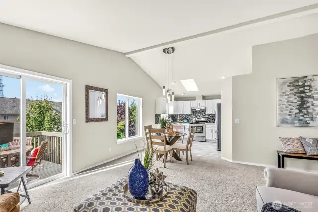 Open-concept living continues into the dining space and kitchen. Vaulted ceilings, broad windows, and deck access create an airy gathering zone that suits both casual meals and larger occasions.