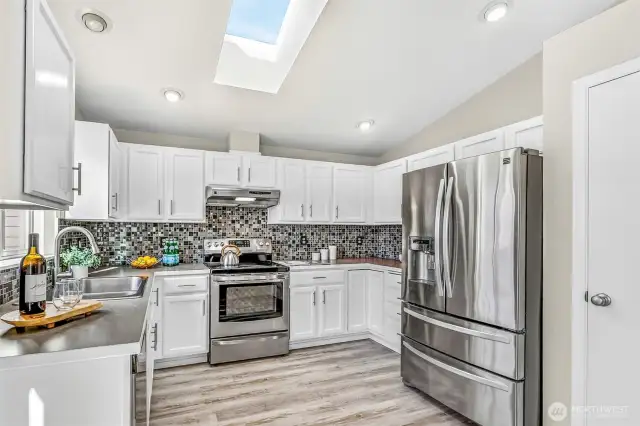 The kitchen’s efficient U-shape provides excellent storage and prep space, complemented by recessed lighting for bright task areas. The skylight enhances the fresh feel and keeps the heart of the home bright throughout the day