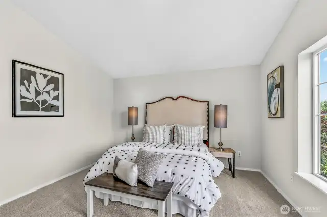 Primary suite retreat with vaulted ceiling, fresh interior paint, and new carpet underfoot. The wide window frames leafy neighborhood views and the generous wall space supports multiple layout options.