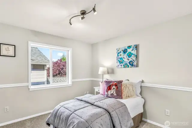 Another upstairs bedroom adds flexibility—note the chair-rail detail and updated ceiling fixture. Soft new carpet and a calm palette create a restful, ready-to-use space.