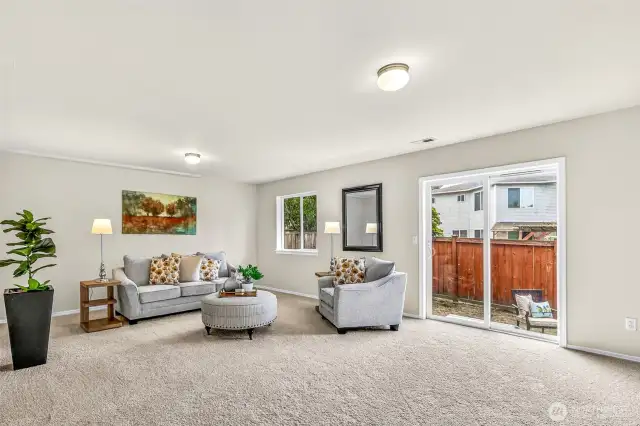 Expansive lower-level bonus room with new carpet and fresh paint—ideal for media, play, workouts, or a second living area. A large slider opens to the backyard for easy indoor-outdoor living.