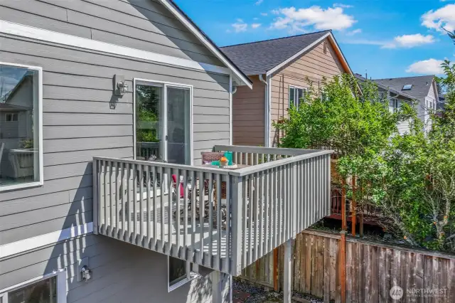 Elevated deck with slider access from the living room. Durable railings and leafy buffers extend the living space outdoors for morning coffee or evening relaxation.