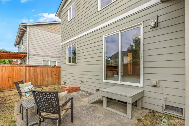 Ground-level patio outside the lower bonus room—ready for casual lounging, container gardening, or setting up a grill station. Fenced boundaries add peace of mind for everyday use.