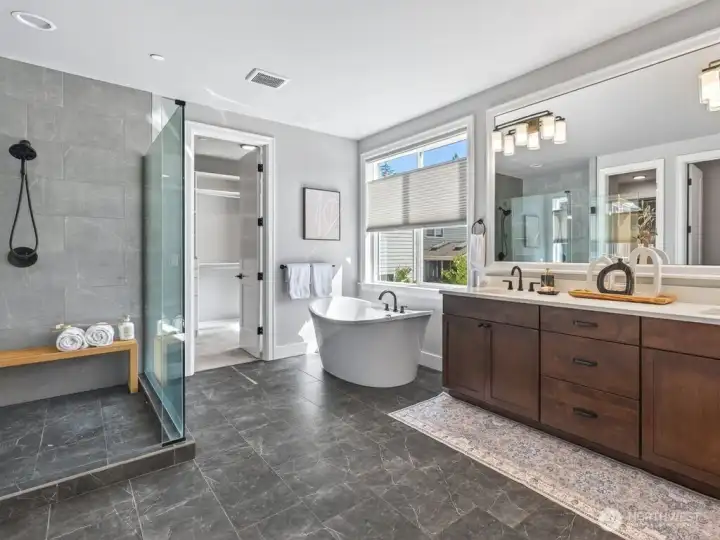 A lavish, spacious, resort-inspired primary suite bath featuring dual sinks and a deep soaking tub.