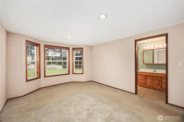 LARGE PRIMARY BEDROOM  Bay windows overlooking rear yard  Hardwood floors under carpet – between floor vent and window