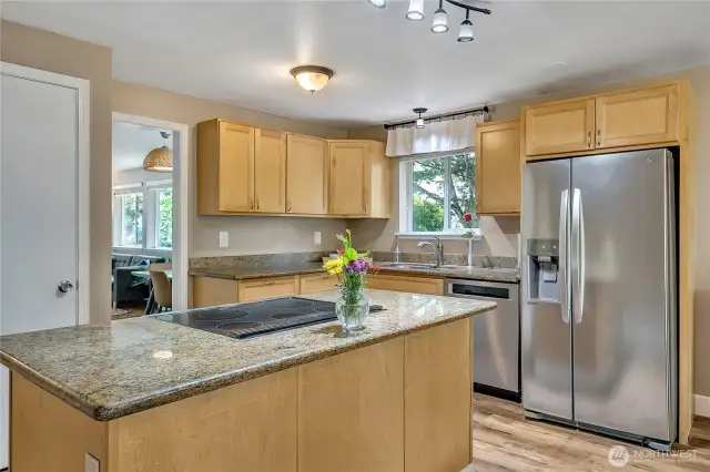 Island kitchen with slab granite and stainless appliances is perfectly located between the dining room and the family room.