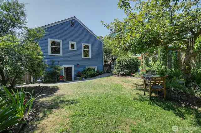 Yard is fenced and has fruit trees and lots of flowering bushes and plants.