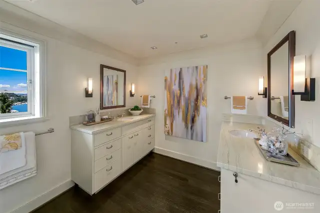 Primary bathroom with two marble and wood vanities, dark oak flooring and nickel fixtures.