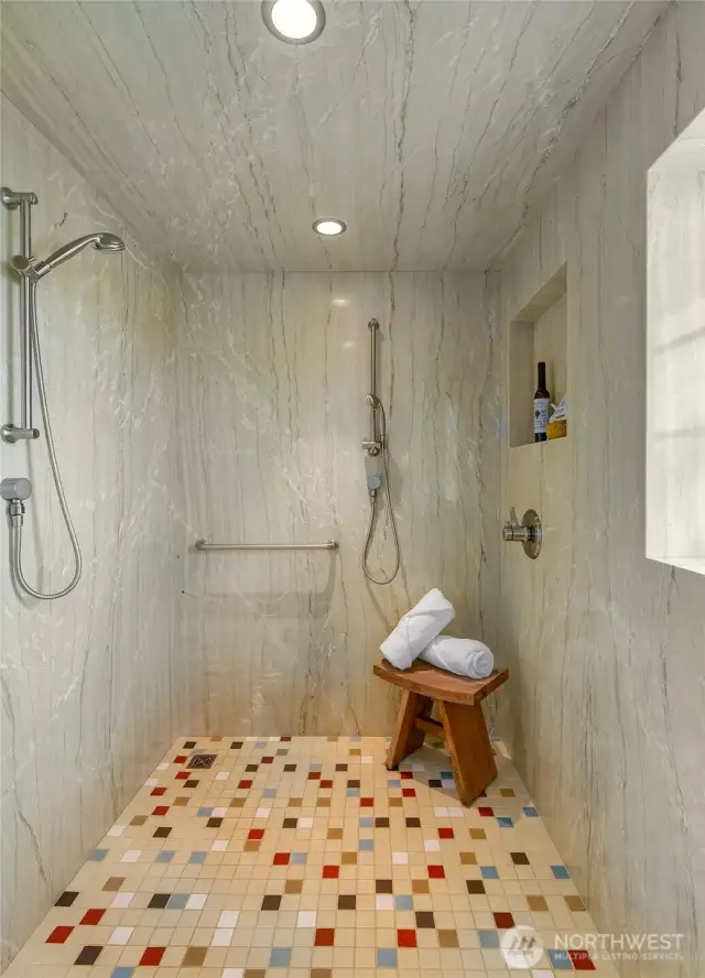 A walk-in shower with floor to ceiling marble walls and tile floor.